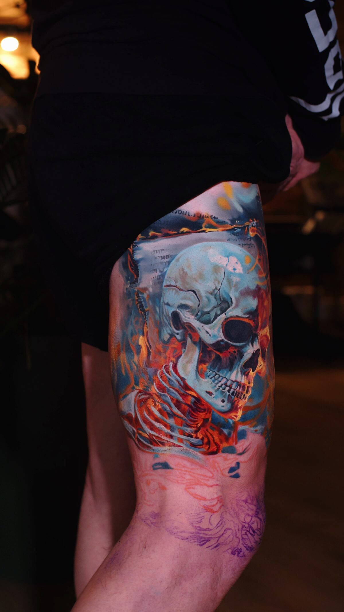 Seitenansicht des Totenkopf-Tattoos in Flammen – in Arbeit, geplante Skelettlinie sichtbar, Alex Vasilevko