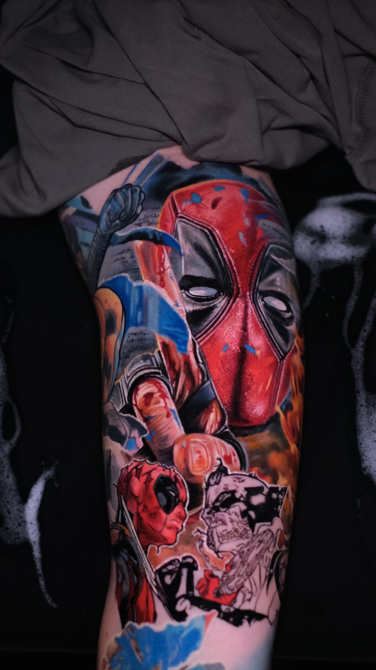 Nahaufnahme der Deadpool-Maske und der Hand mit Mittelfinger und Blutstropfen – Color-Realism auf dem Arm, Breslau.
