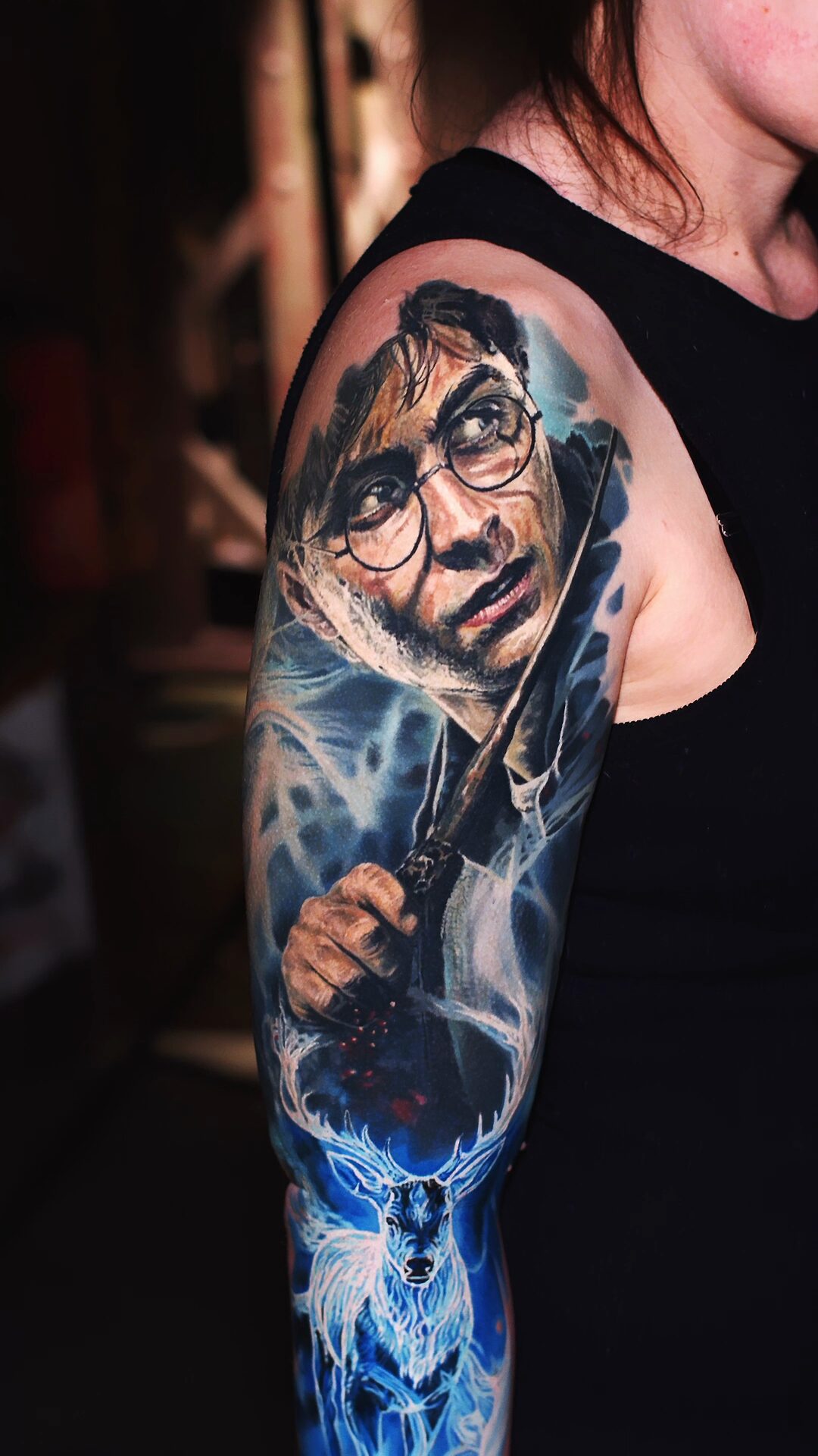 Nahaufnahme von Harrys Gesicht: warme Hauttöne im Kontrast zum kühlen, blauen Hintergrund – Tattoo am Oberarm