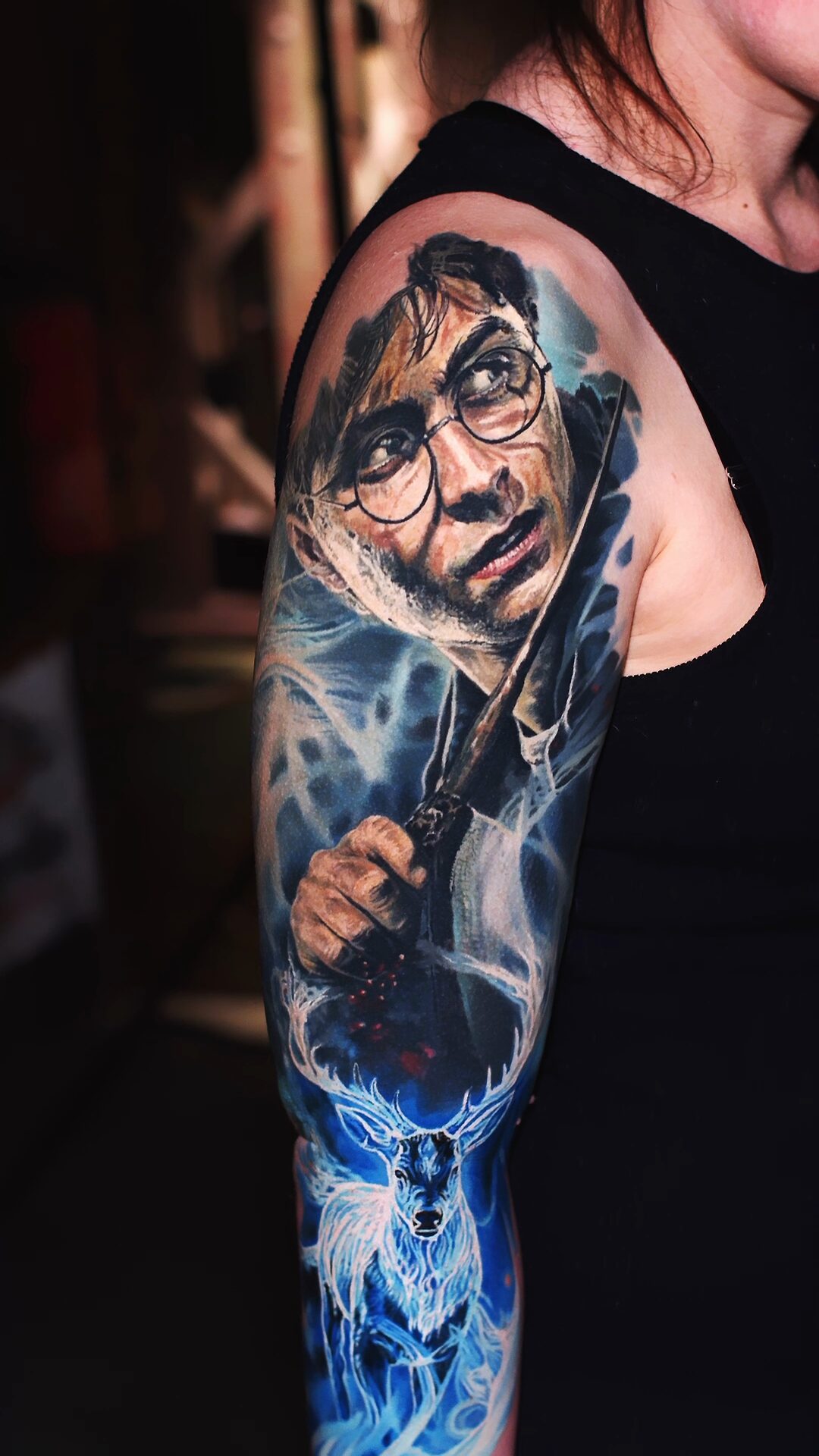 Rote Funken aus dem Zauberstab – Detail des farbigen Tattoos am Unterarm, Color-Realism