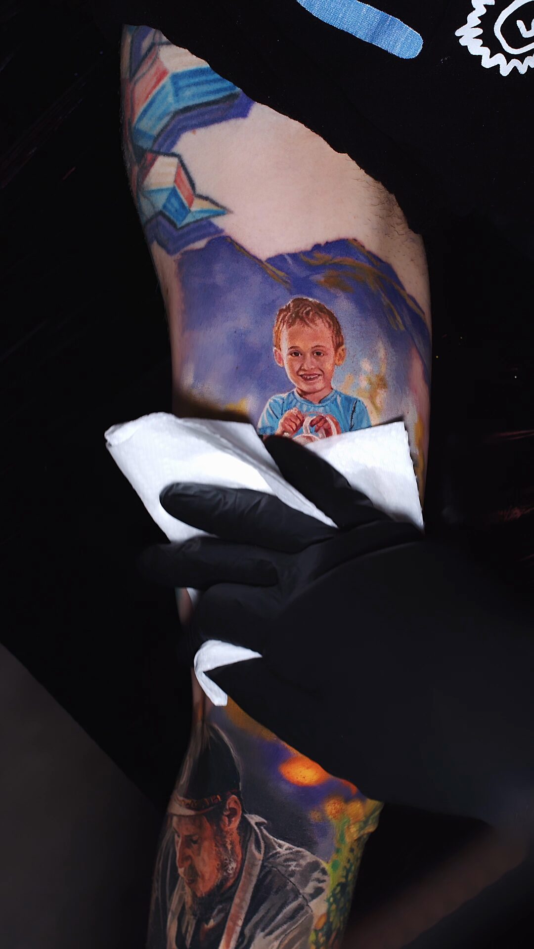 Ausschnitt mit Holzzaun und grünem Hintergrund – Porträt nach Foto, Tattoo am Bizeps, Realismus