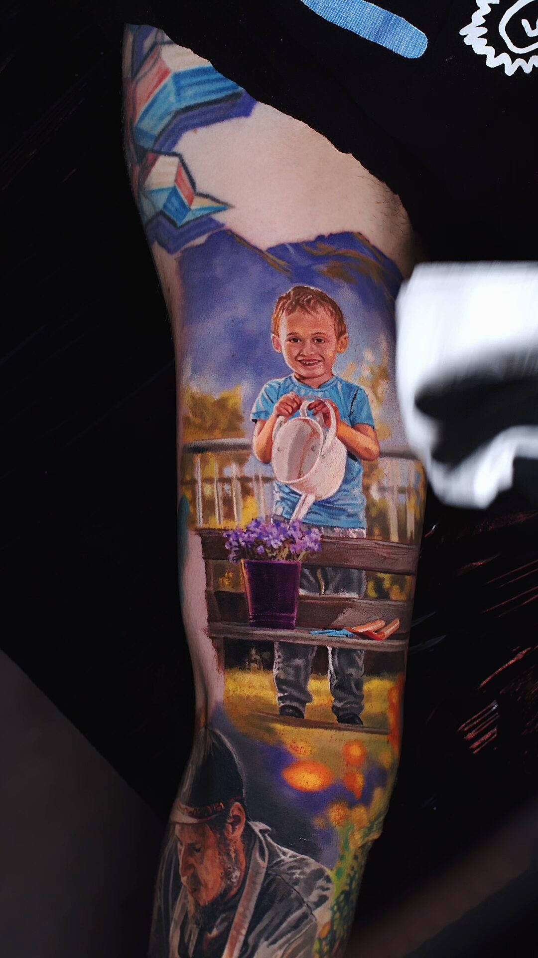 Gesamtkomposition des Tattoos am Bizeps – Porträt des Sohnes, Familienszene, künstlerisches Tattoo in Breslau