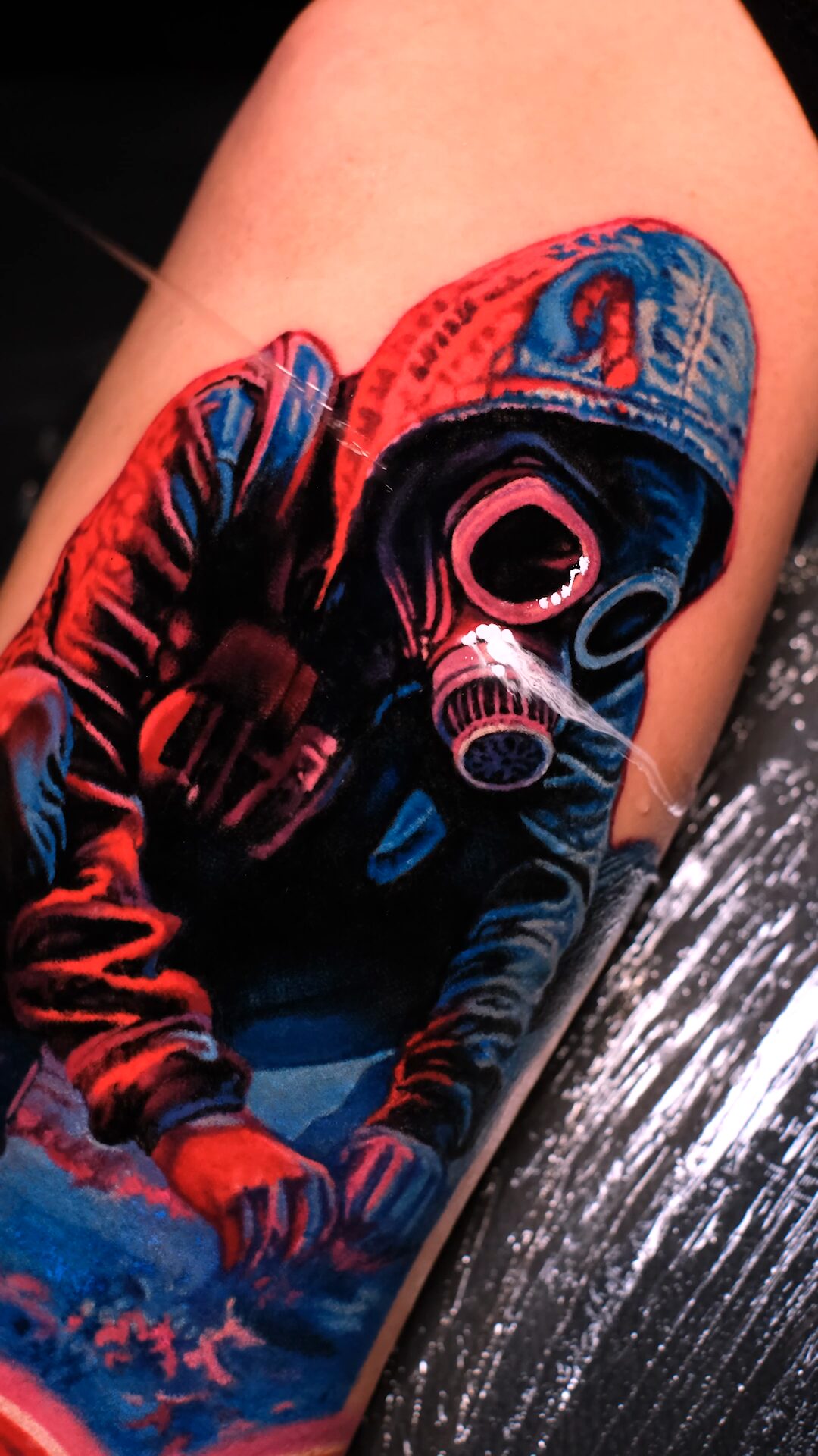 Ganze Figur mit Kapuze und Gasmaske auf dem Oberarm – Aufsicht, blauer Grund unten, Wrocław.