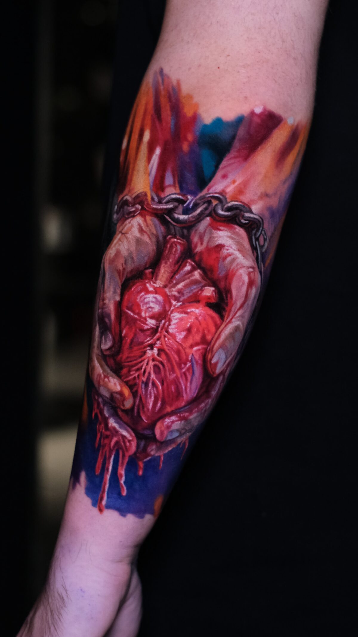 Gesamtansicht des Tattoos auf dem Unterarm – anatomisches Herz in Händen, Kette, Watercolor, Wrocław