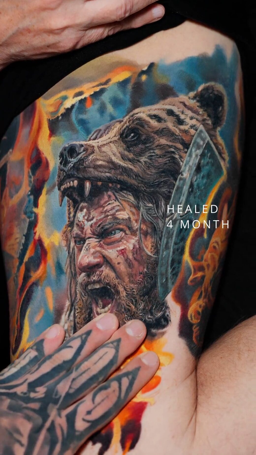 Nahaufnahme vom Gesicht des Berserkers und der Bärenkopf-Kappe, Hand des Tätowierers unten, Tätowierer Wrocław.